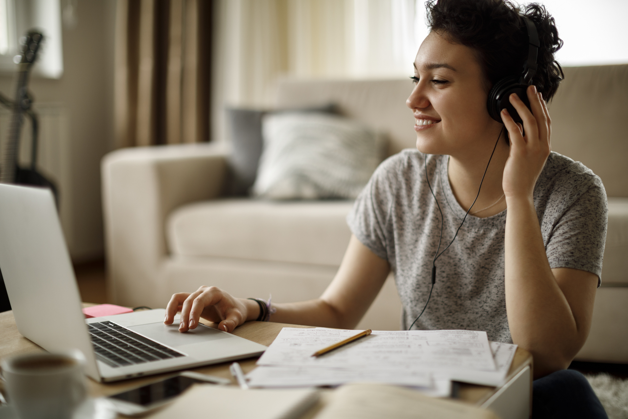 Young woman using laptop and listening to music at home